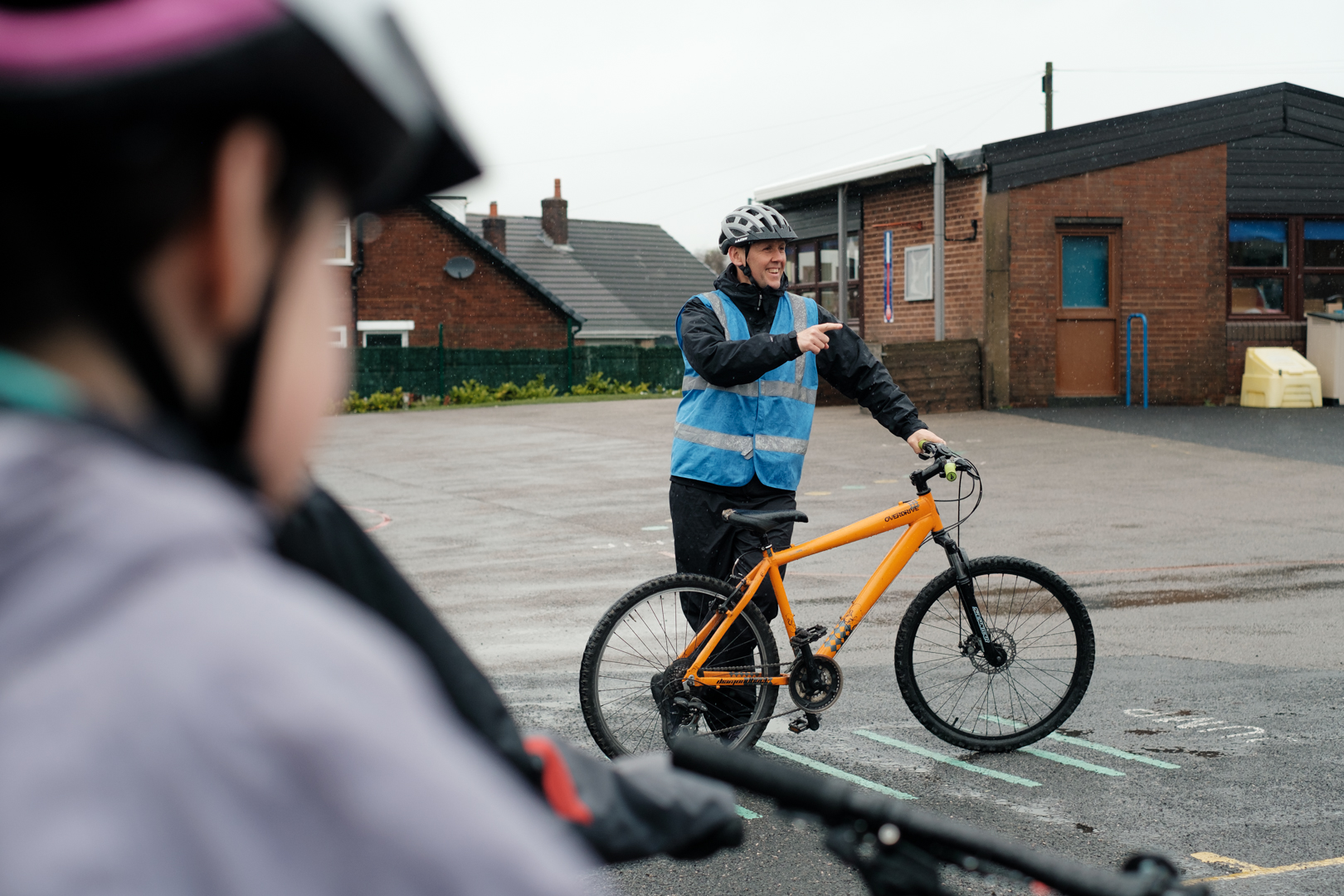 An instructor in the playground giving riders some instructions. He is grinning