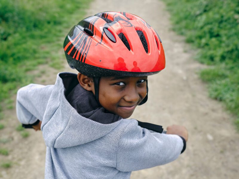 A child wearing a red cycle helmet looking back at the camera and smiling