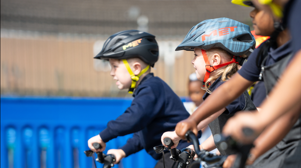 Bikeability riders on balance bikes are lined up in a playground ready to cycle