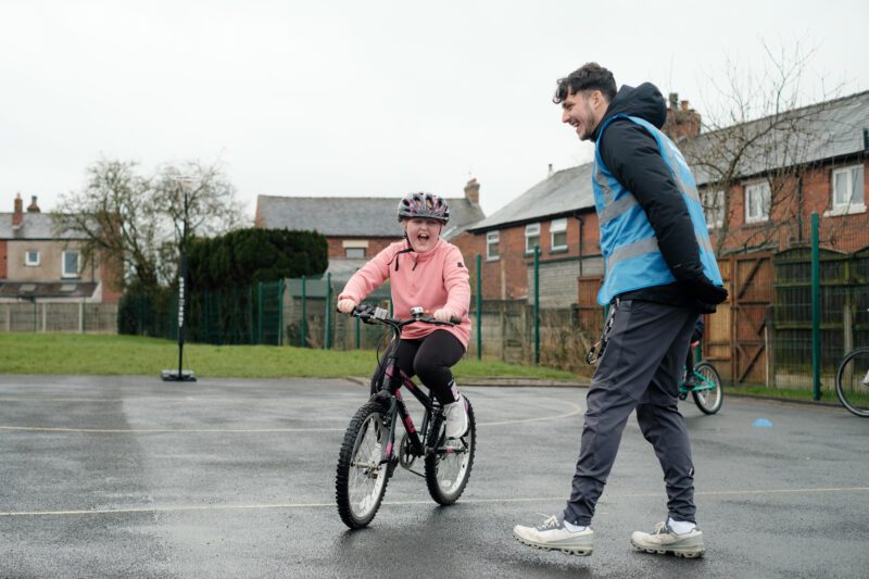 Instructor Will Joy with a Bikeability student in a playground.