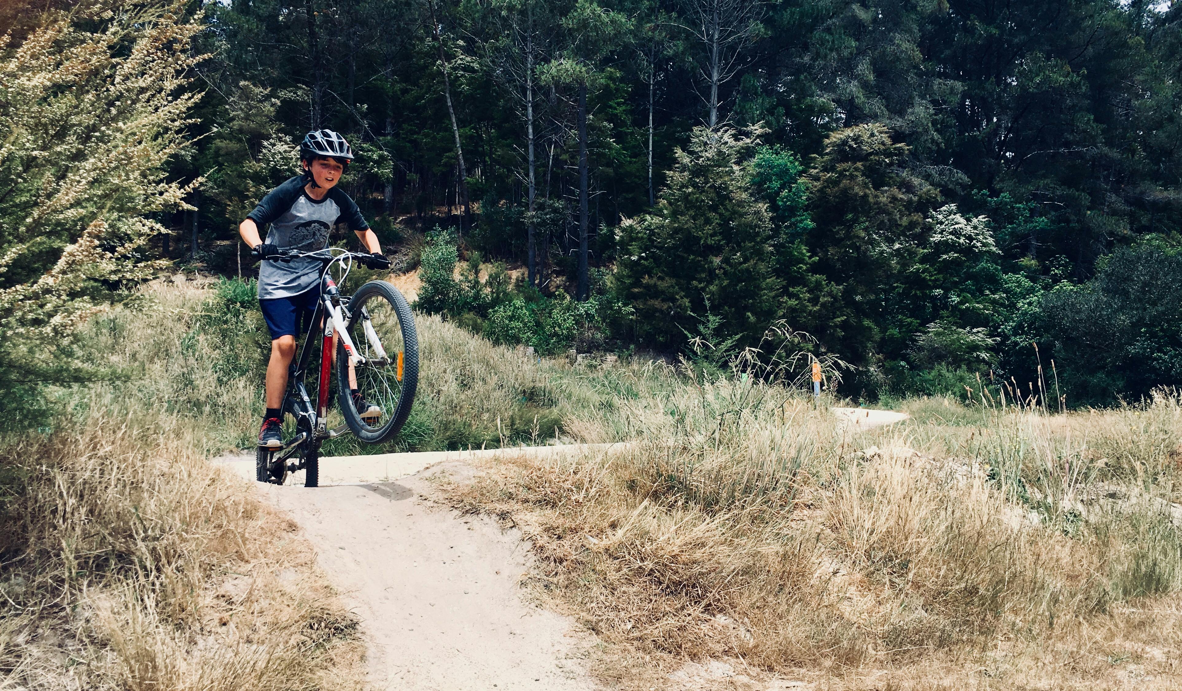 A boy on a mountain bike is riding up a hill. The front wheel is off the ground.