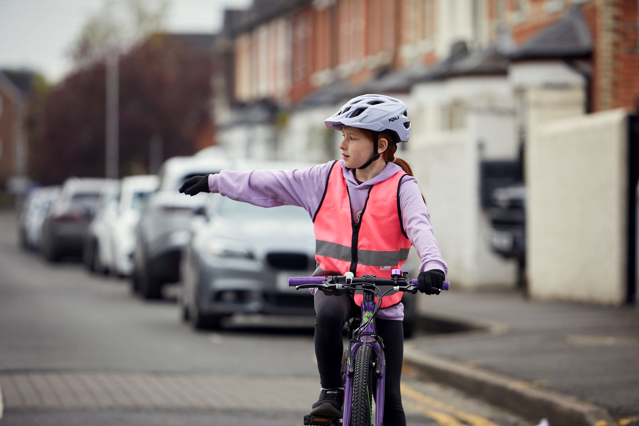 A girl cycling on a road is signalling that she wants to turn right