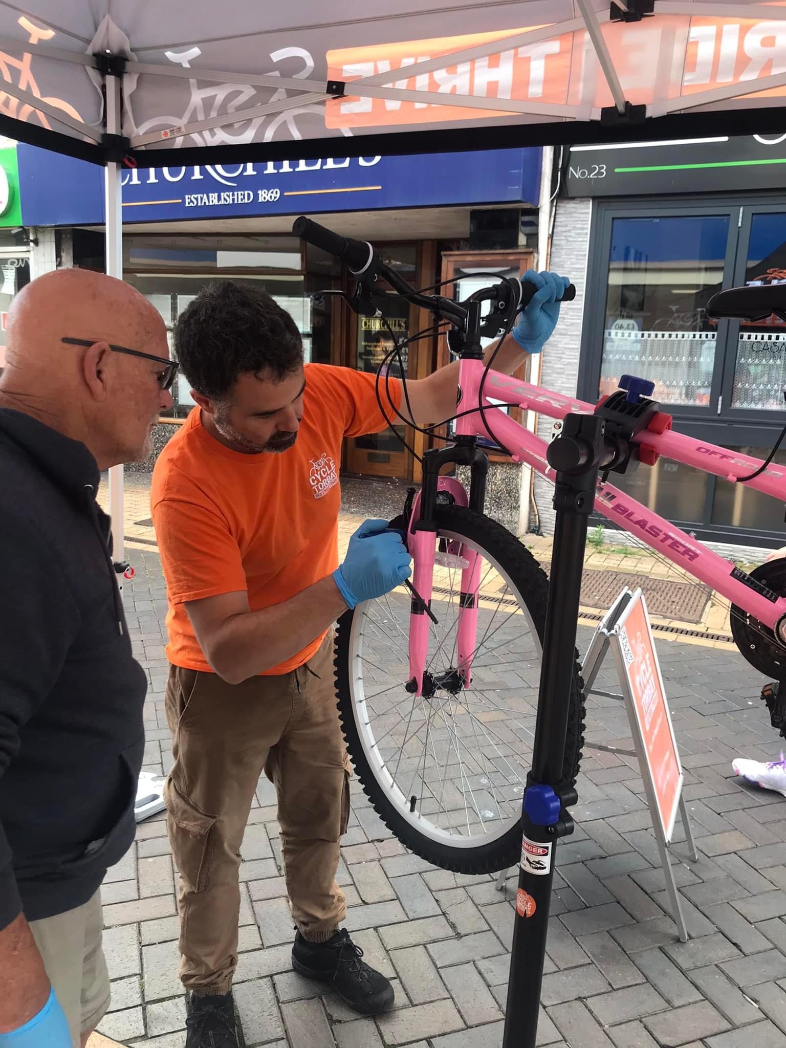 Instructor Jon at a Dr Bike session helping fix a bike that is on a stand