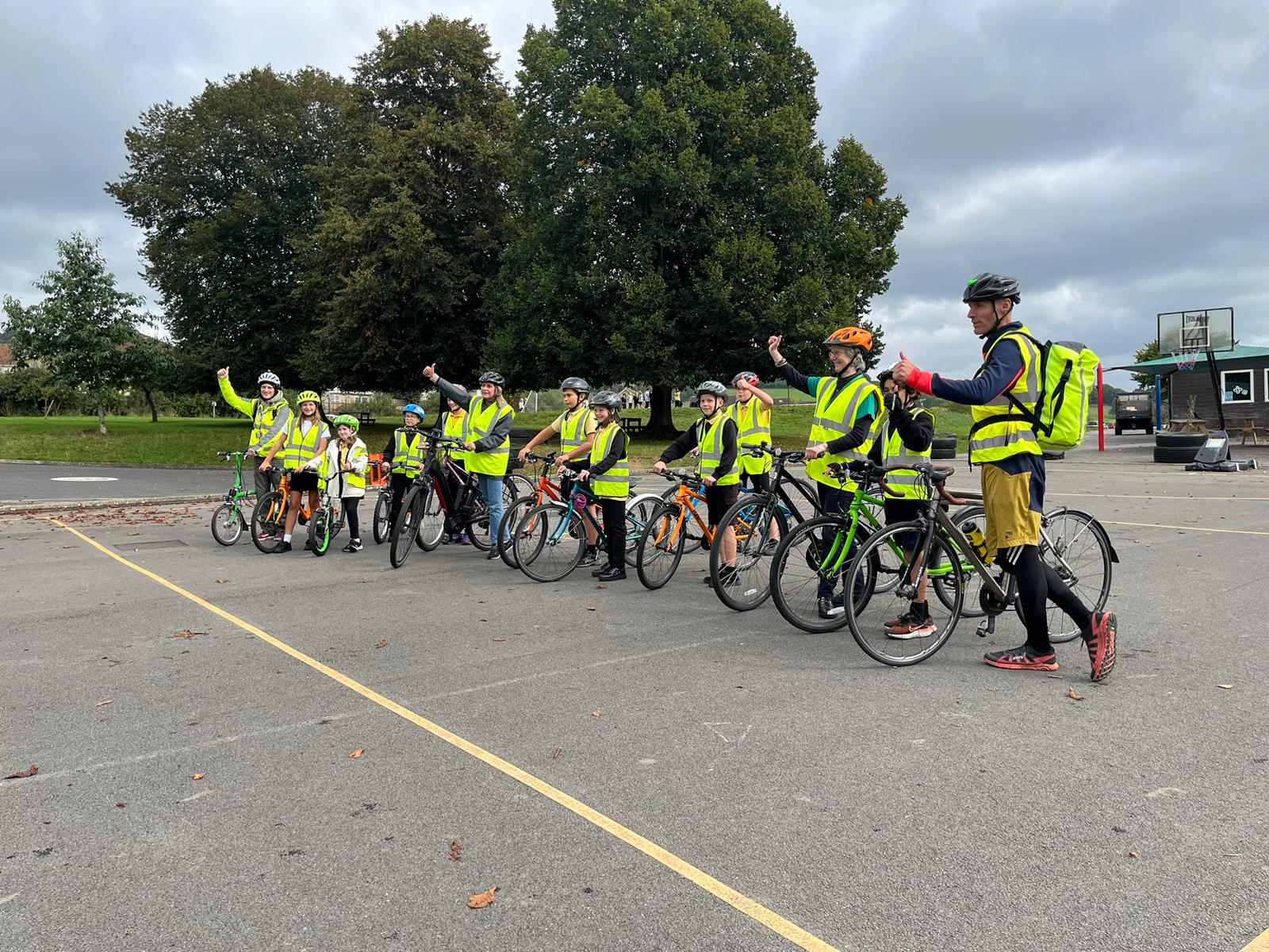 A group of children and their teachers in the playground with bikes, they are wearing hi-vis