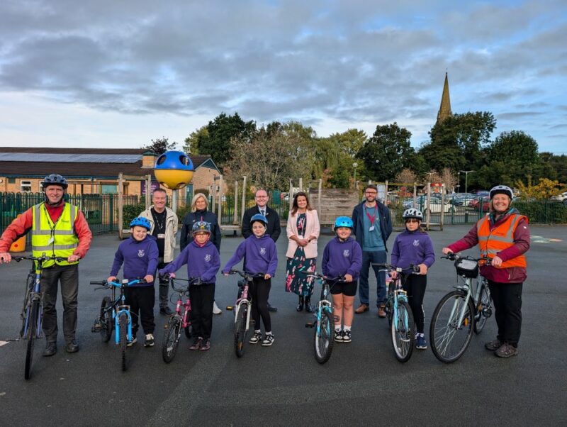 A group of students, teachers and Bikeability instructors with their bikes smiling