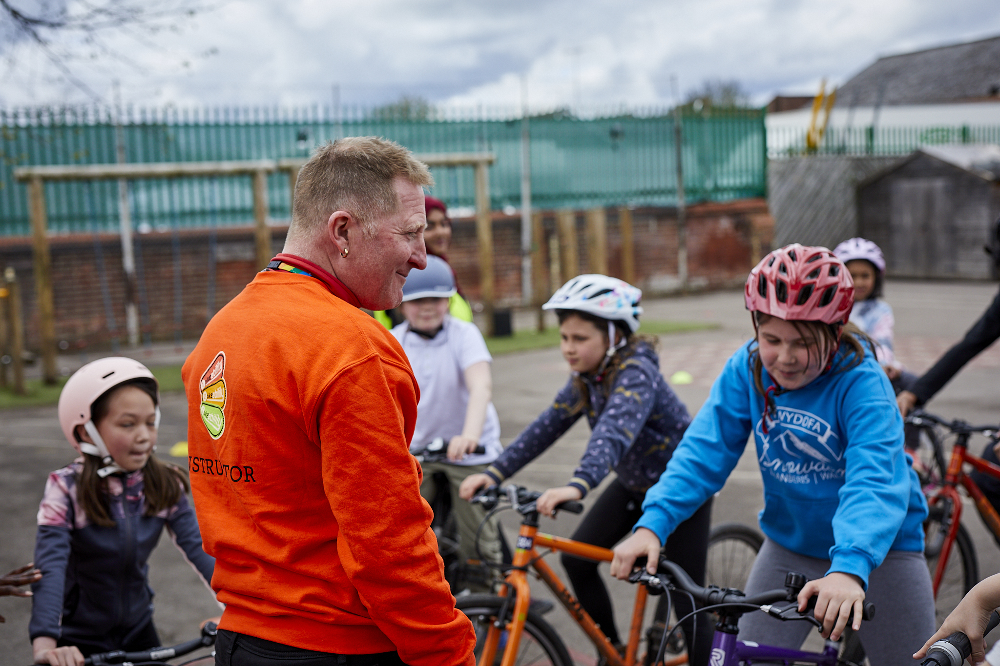 A Bikeability instructor talking to riders on their bikes in a playground